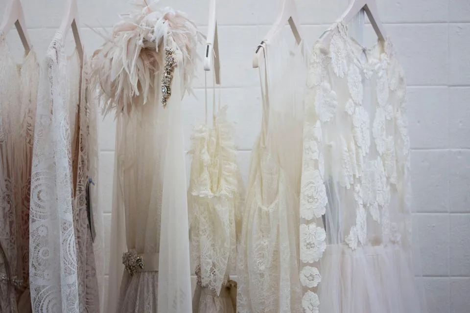 White dresses on hangers against a brick wall